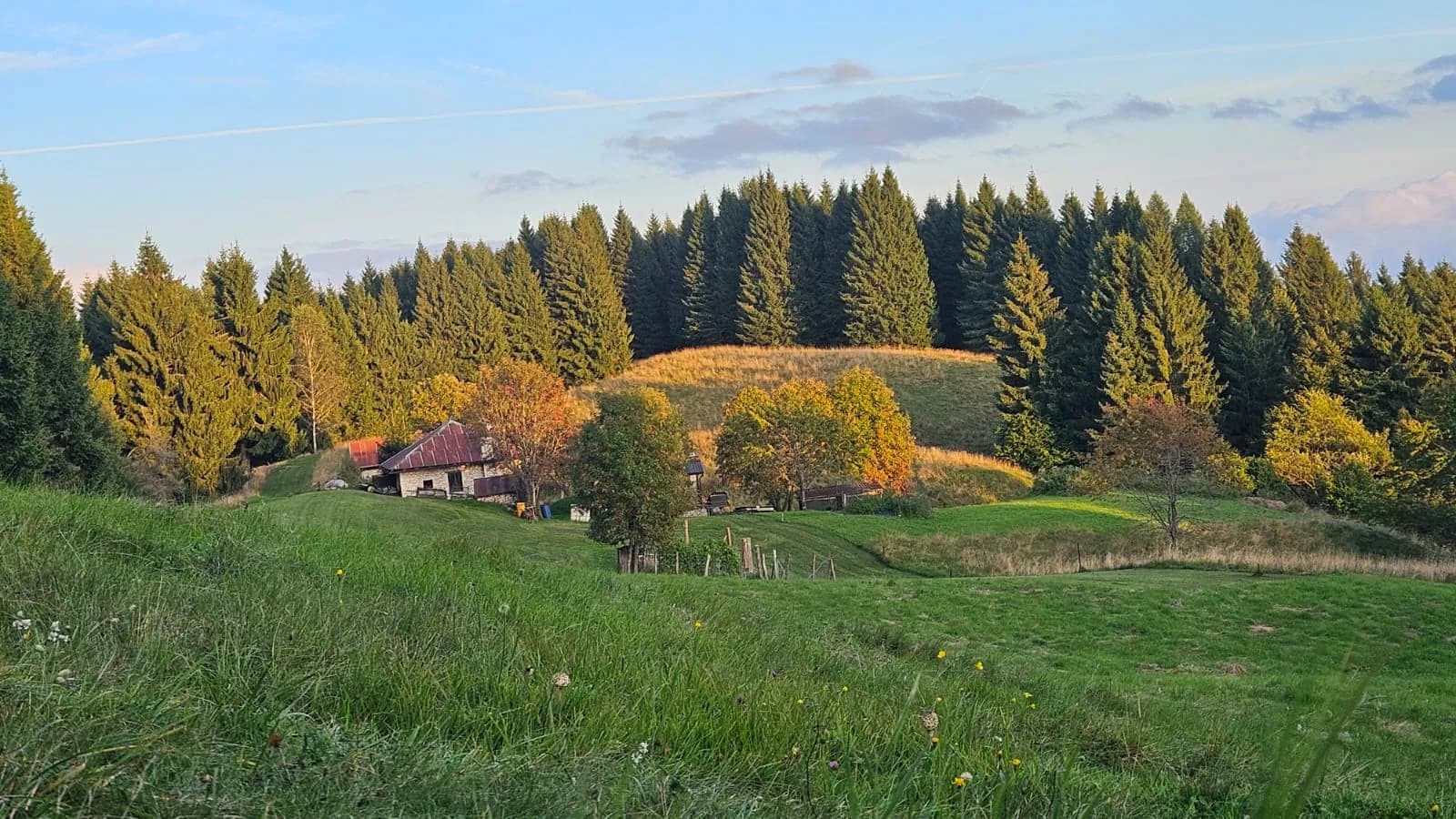 Il maso tra i prati e gli alberi nella luce della sera